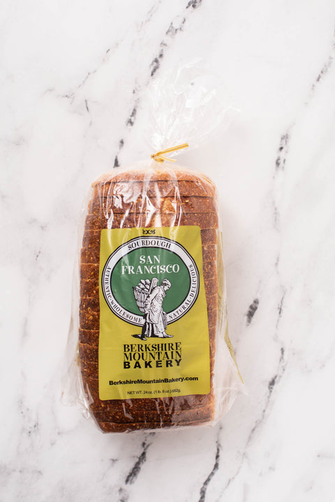 A freshly baked dark golden brown San Francisco style pan loaf in a bag by Berkshire Mountain Bakery