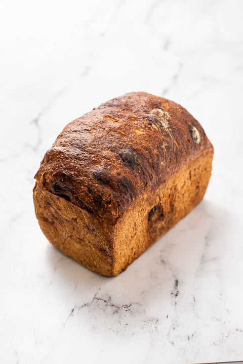 Spelt raising pan loaf with a brown crust on a marble countertop