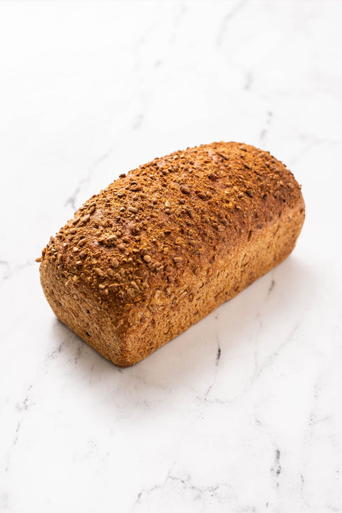 Loaf of sunny flax bread baked and browned on a maple countertop